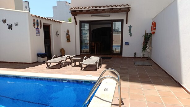 Una piscina con sillas de descanso y un porche cubierto.