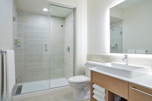 A modern bathroom with a glass shower enclosure, a white toilet, and a wooden vanity with a sink. - Element by Marriott Basalt - Aspen (Basalt)
