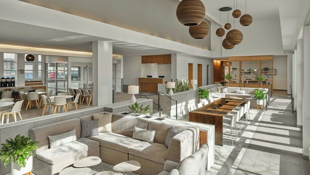 A spacious hotel lobby with a long dining table, sofas, and a kitchen area in the background. - Element by Marriott Basalt - Aspen (Basalt)