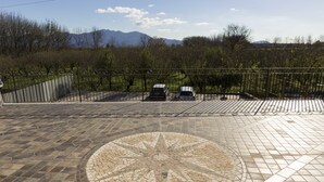 A paved area with a circular mosaic design, a metal fence, and parked vehicles. - Ascot Hotel (Caianello)