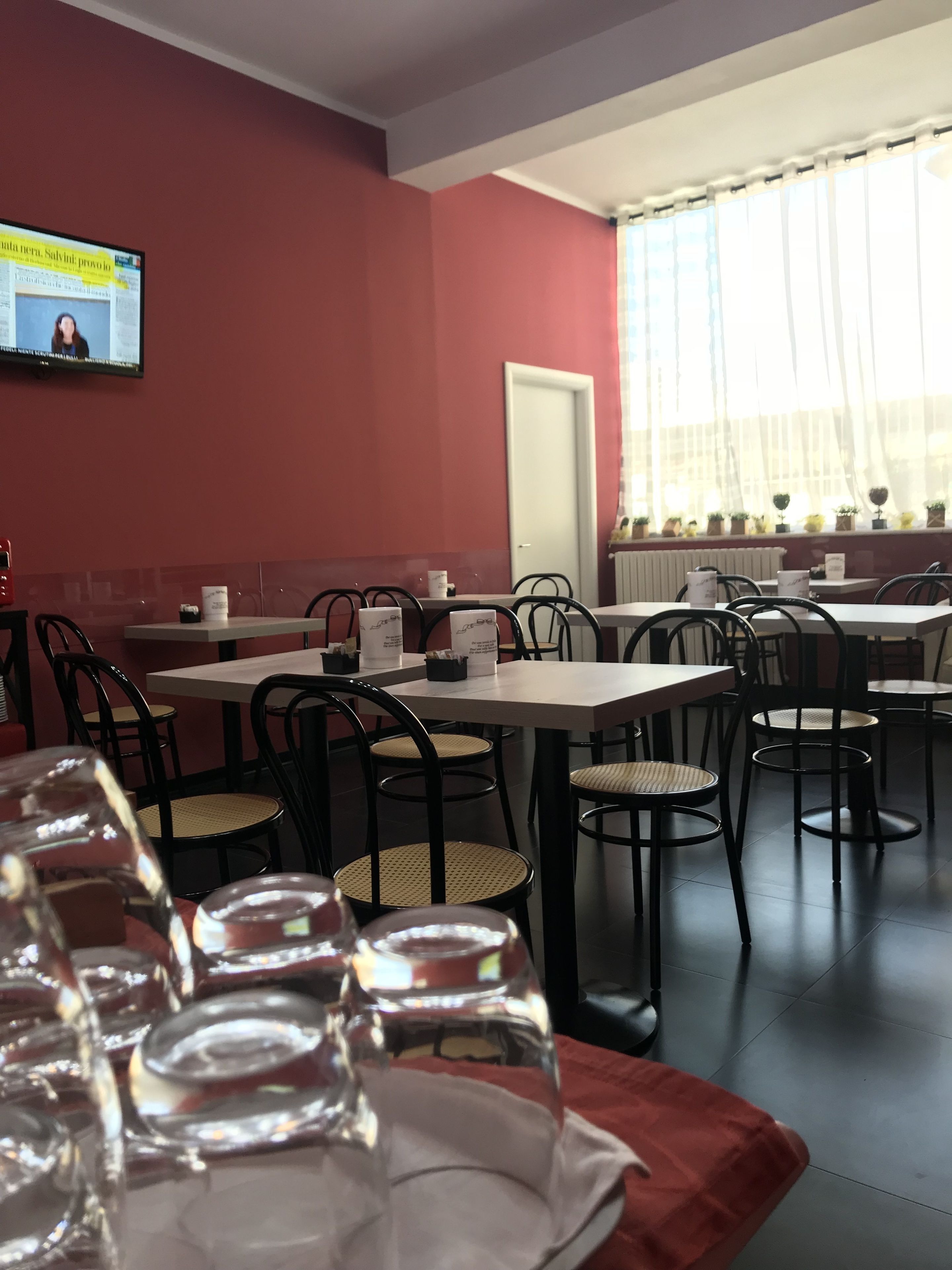 Ein Restaurant mit Tischen und Stühlen, einem Fernseher an der Wand und einem Fenster mit Vorhängen.