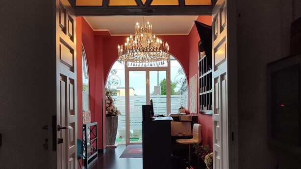 A hallway with a chandelier, a reception desk, and a view of the outside. - Ascot Hotel (Caianello)