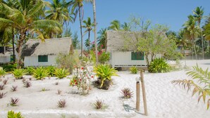 A beachfront property with thatched-roof cottages, sandy beach, and tropical vegetation. - Cristal Resort (Paje)