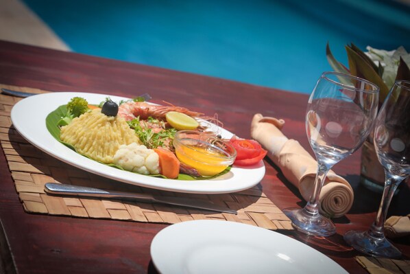 A dining table with a plate of food, a glass of water, and a rolled napkin. - Cristal Resort (Paje)