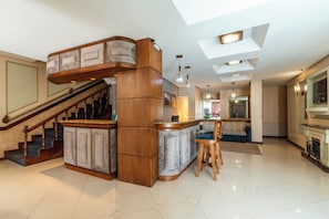 A spacious living area with a wooden staircase, a bar area, and a kitchen. - Hotel Vista do Vale (Gramado)