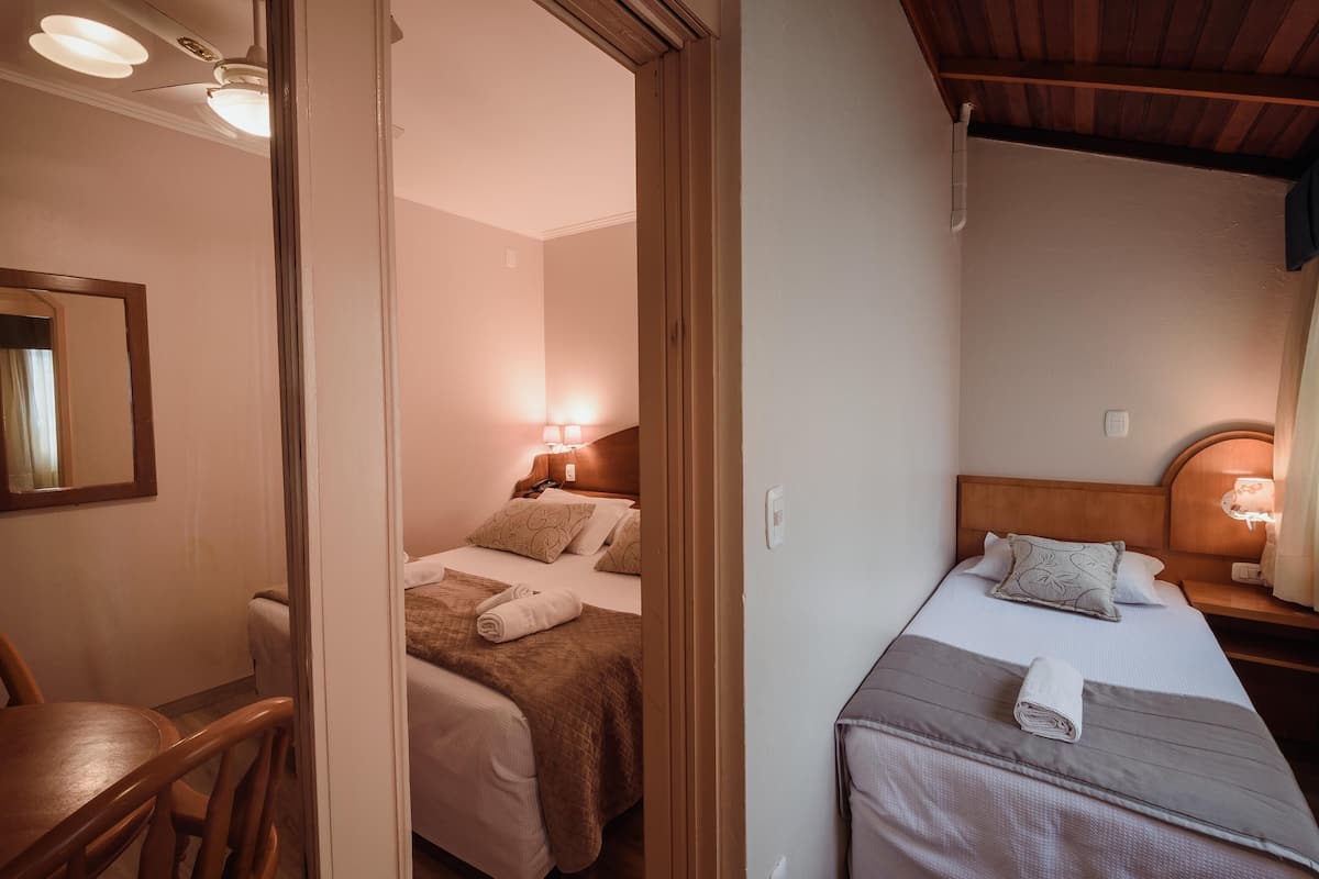 A hotel room with two beds, a wooden headboard, bedside lamps, and a mirror on the wall.
