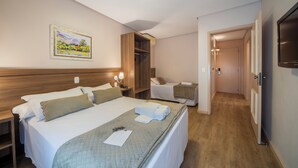 Habitación de hotel con dos camas, un armario de madera, un cuadro en la pared y un televisor.
