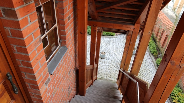 Una escalera de madera que conduce a un edificio de ladrillo con una ventana y una maceta en el suelo.