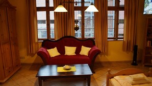 Un salón acogedor con un sofá rojo, una mesa de centro de madera y una ventana con cortinas.