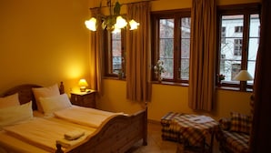 Habitación de hotel con cama, lámpara de noche, cortinas, una mesita y una silla.