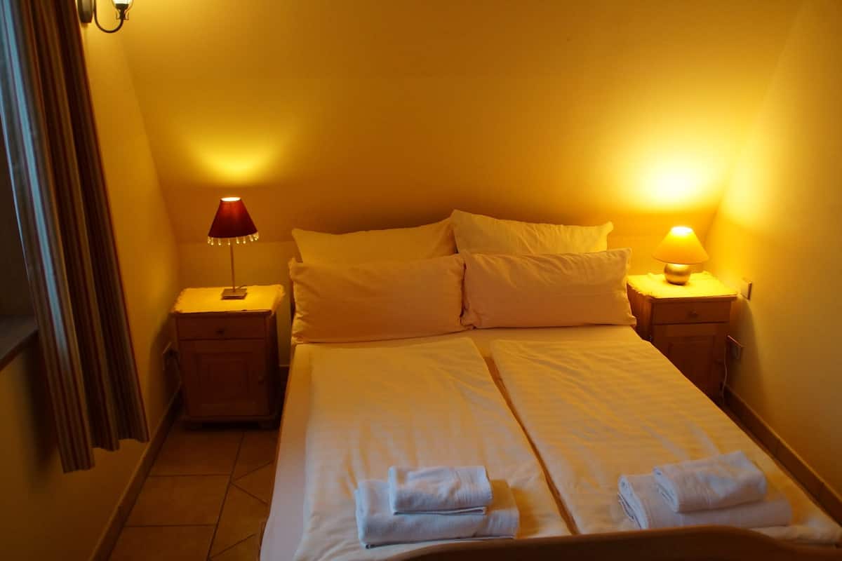 A hotel room with a bed, two bedside tables, and two lamps.