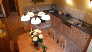 Una cocina con armarios de madera, encimera negra, pileta de acero inoxidable y candelabro con varias luces.