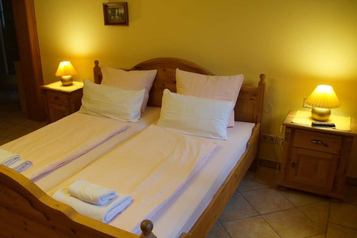 A double bed with white linens, two bedside tables with lamps, and a wooden headboard.