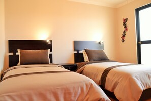 Una habitación de hotel con dos camas, cada una con cabecera y mesitas de noche.