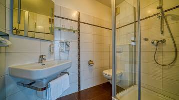 A modern bathroom with a glass-enclosed shower, a white sink, and a toilet.