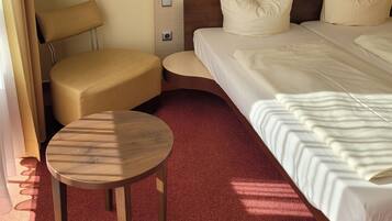 Ein Hotelzimmer mit einem großen Bett, einem kleinen runden Tisch, einem Stuhl und einem Holzkopfstück.