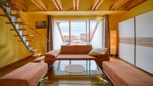 A modern living room with a glass coffee table, a sofa, and a staircase. - Hotel Wissers by ANS (Fehmarn)
