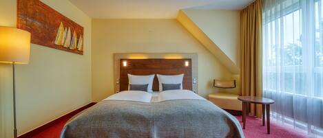 Una habitación de hotel con una cama grande, una mesita de noche, una lámpara y un cuadro en la pared.
