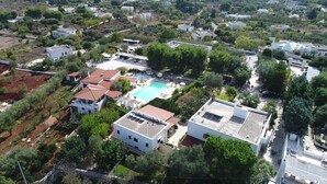 An aerial view of a residential area with houses, a swimming pool, and surrounding greenery. - Agriturismo Salinola (Ostuni)