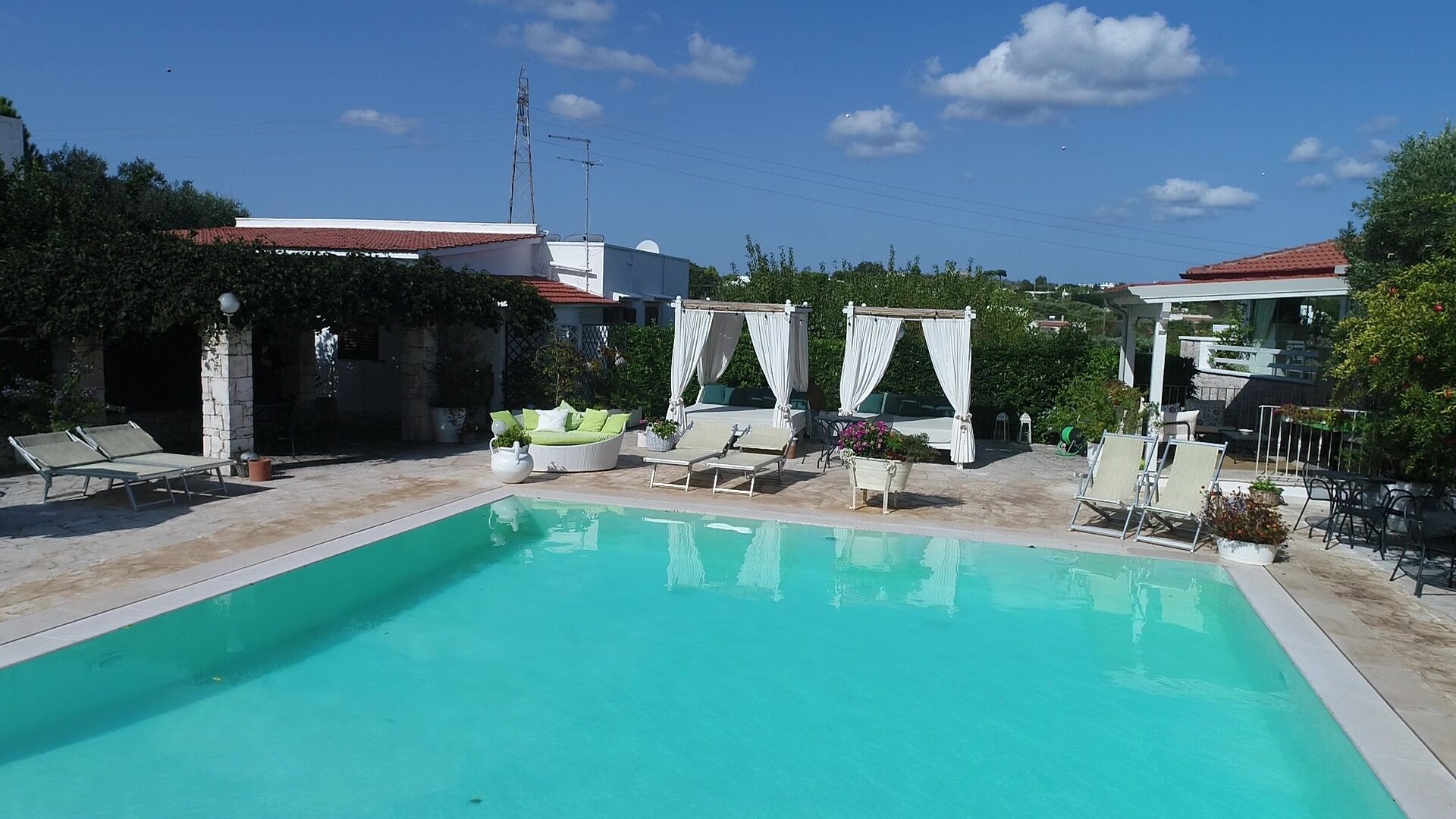 Una piscina con sillas de descanso y una estructura tipo sombrilla.