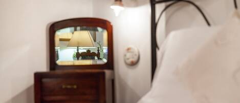 Un dormitorio con cama, mesita de noche, lámpara y aplique de pared.