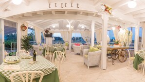 A covered outdoor dining area with checkered tablecloths, wicker furniture, and a view of the landscape. - Agriturismo Salinola (Ostuni)