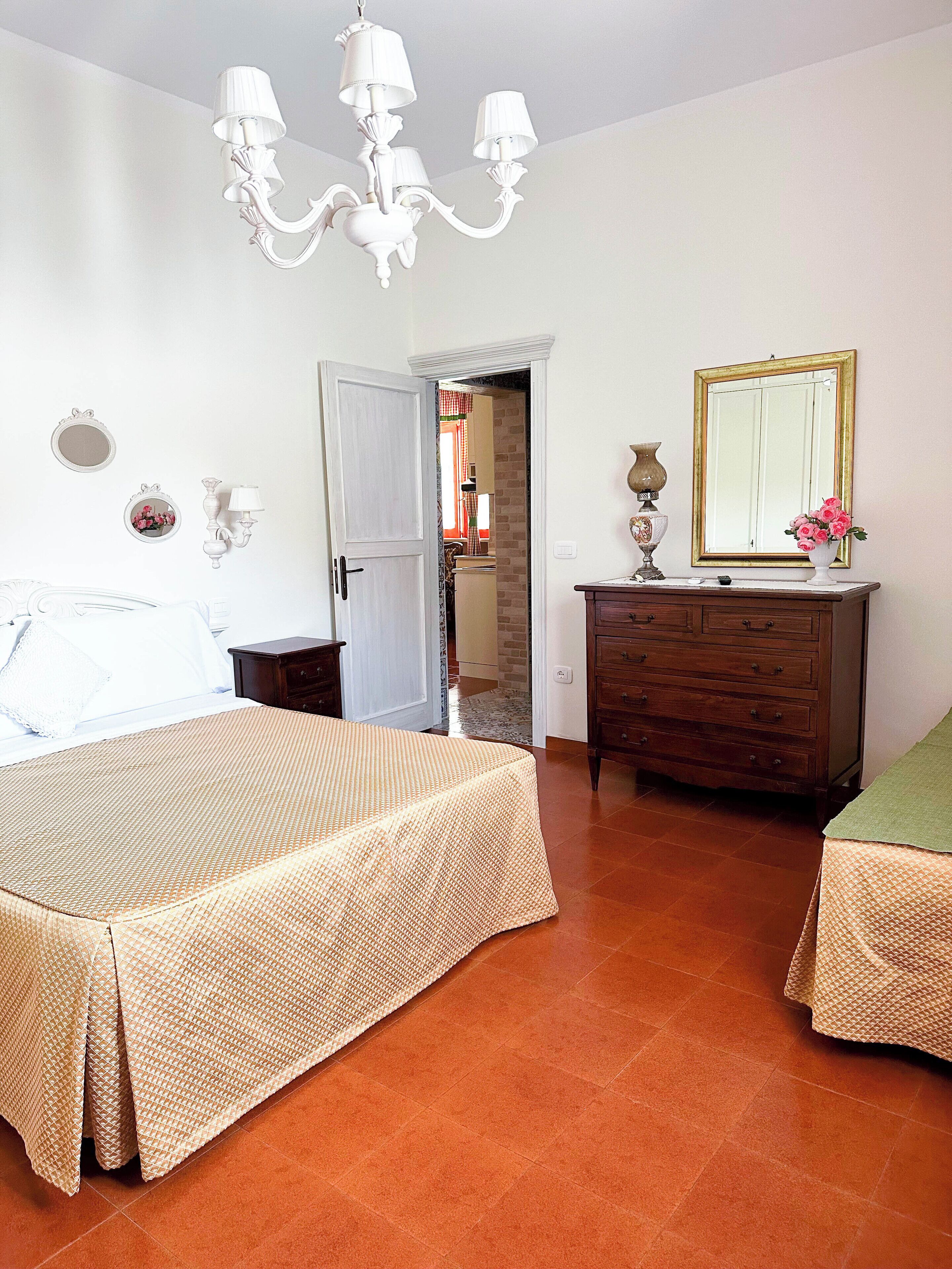 Ein Schlafzimmer mit zwei Betten, einem Schminktisch, einem Spiegel und einer Kronleuchter.