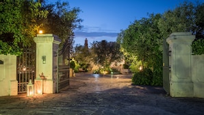 A paved courtyard with a gated entrance, surrounded by greenery and illuminated by lanterns. - Agriturismo Salinola (Ostuni)