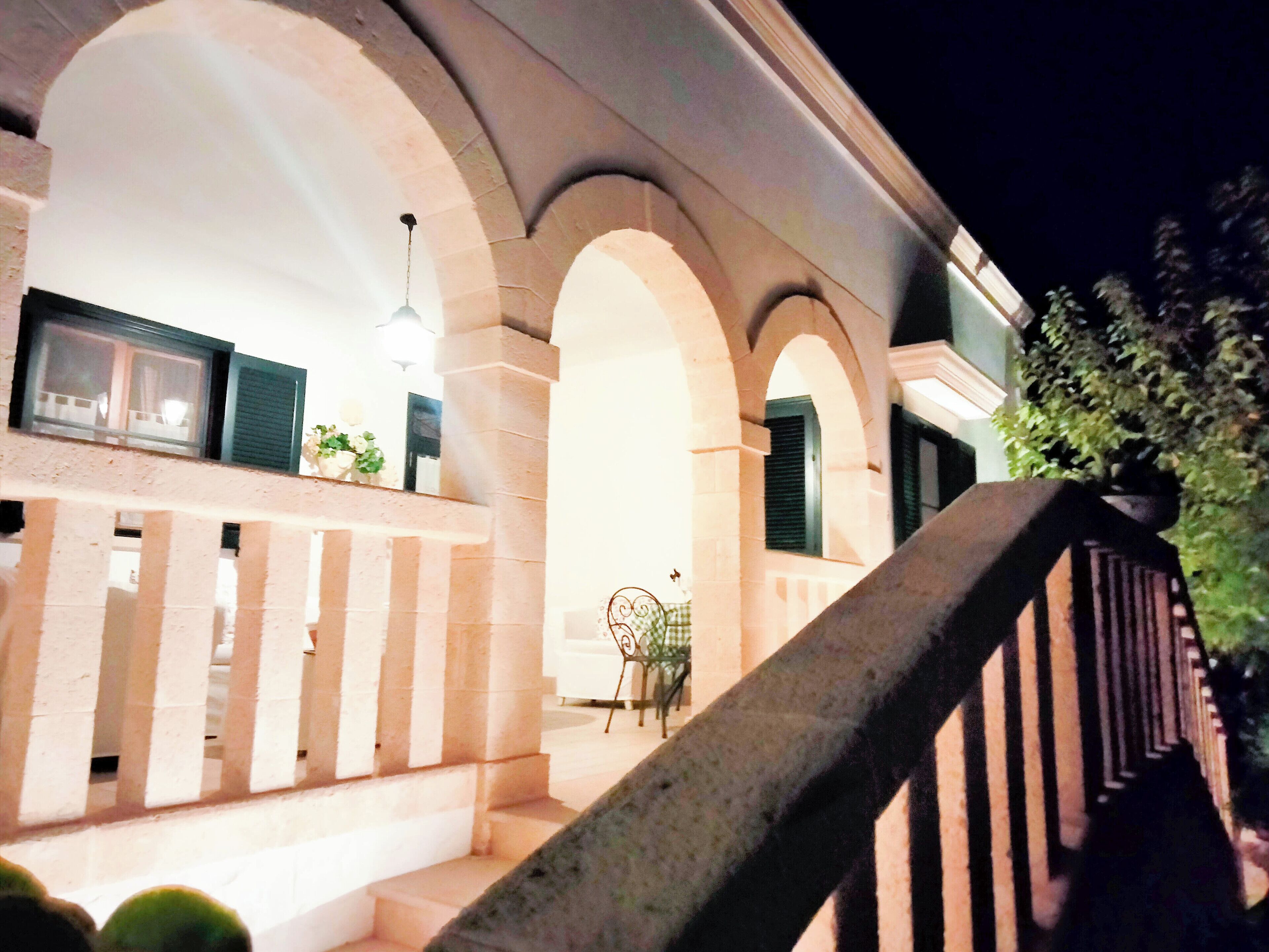A building with a stone facade, arched windows, and a staircase with a metal railing.