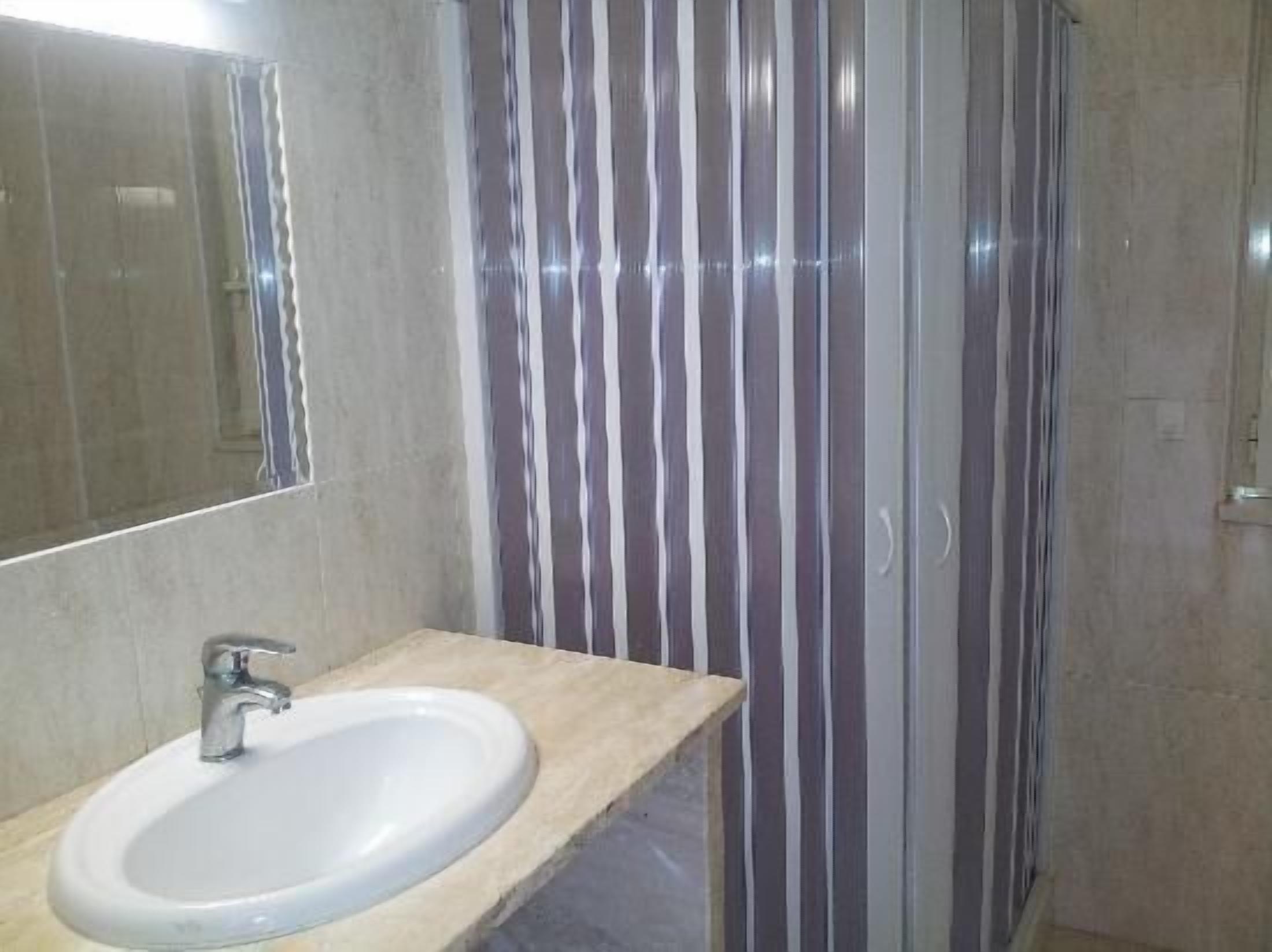 A bathroom with a sink, mirror, and striped shower curtain.