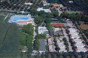 Vista aérea de um bairro residencial com várias casas, uma piscina e quadras de tênis.