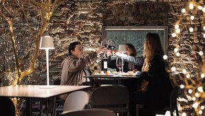 Un restaurante con paredes de piedra, mesas, sillas y luces colgantes.