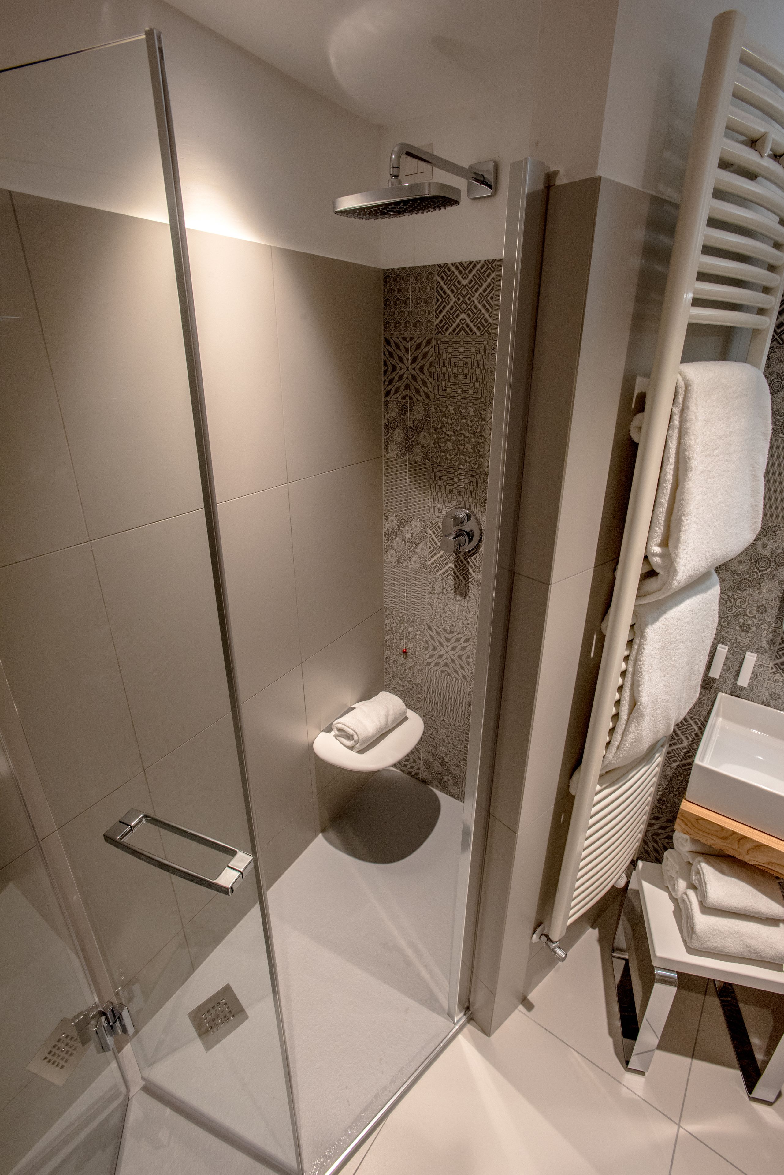 A modern bathroom with a glass-enclosed shower, a white sink, and a towel rack.