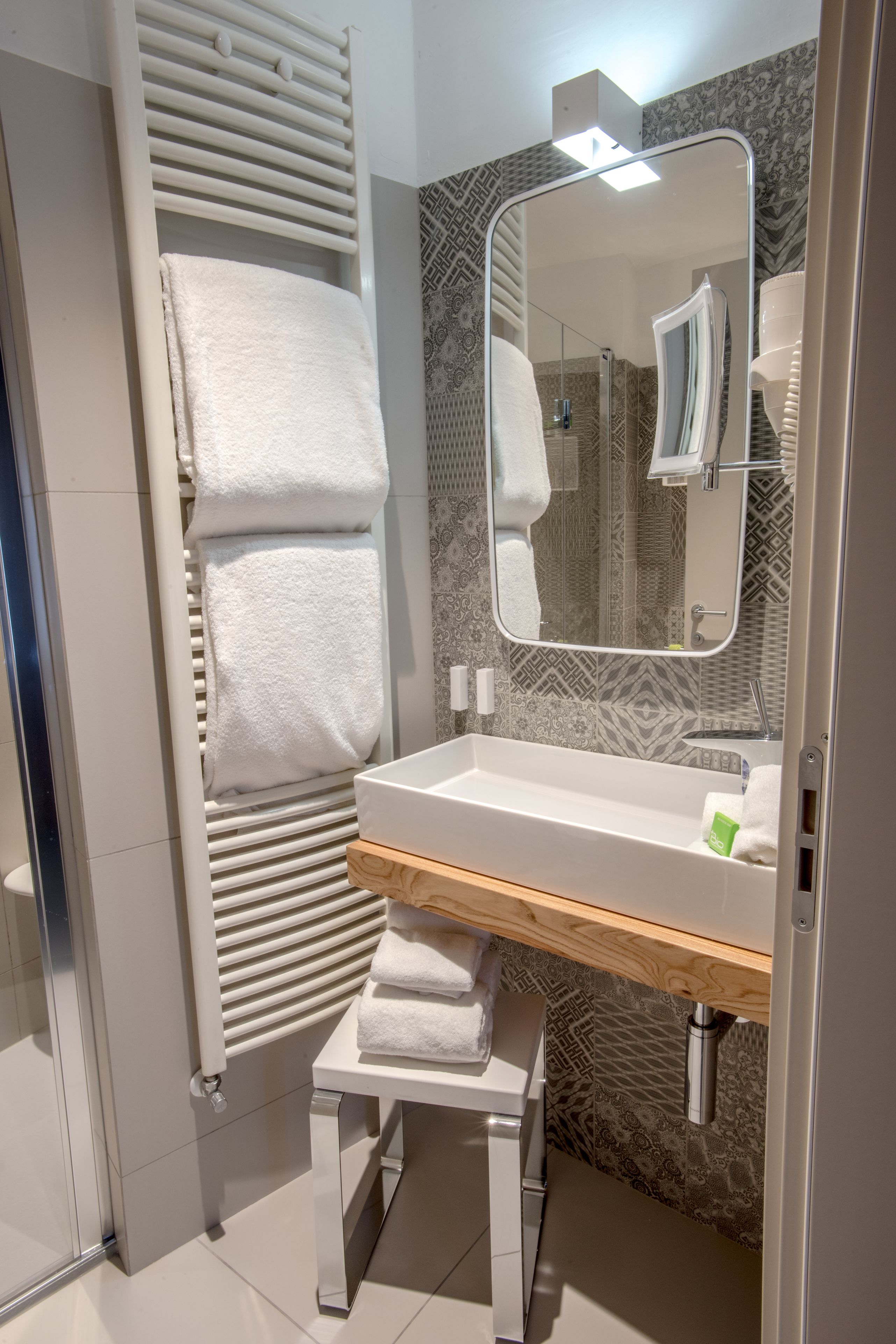 Casa de banho moderna com lavatório branco, espelho e porta-toalhas.