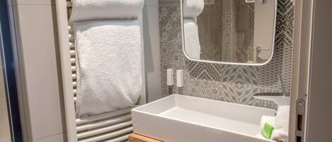 A modern bathroom with a white sink, a mirror, and a towel rack.