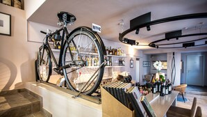 Un interior moderno con una bicicleta exhibida, una zona de bar con botellas y una escalera que lleva a otro nivel.