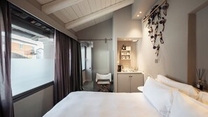 Habitación de hotel con una cama grande, una kitchenette pequeña, un espacio de descanso y vistas al exterior.