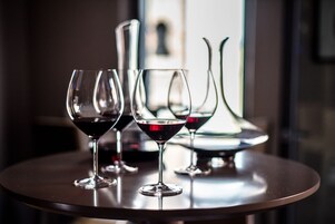 Three wine glasses on a round table with a blurred background.