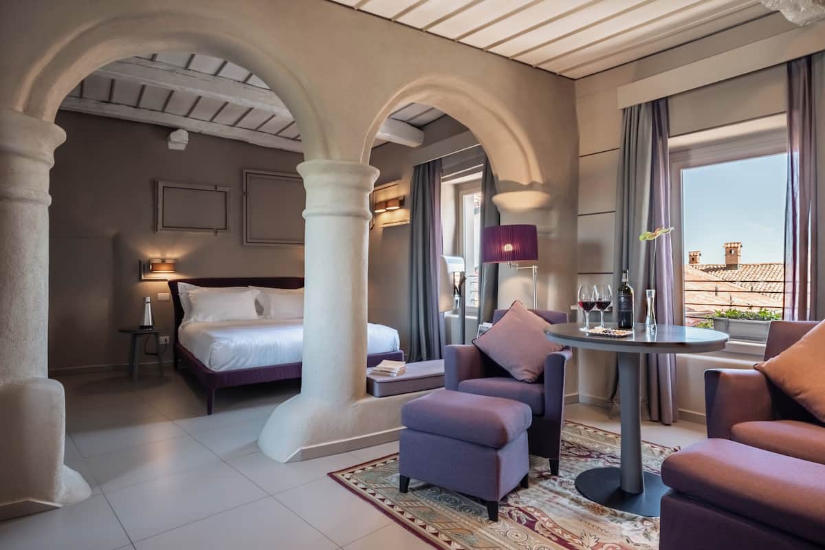 Une chambre d’hôtel avec un lit, un coin salon et une table avec des boissons.