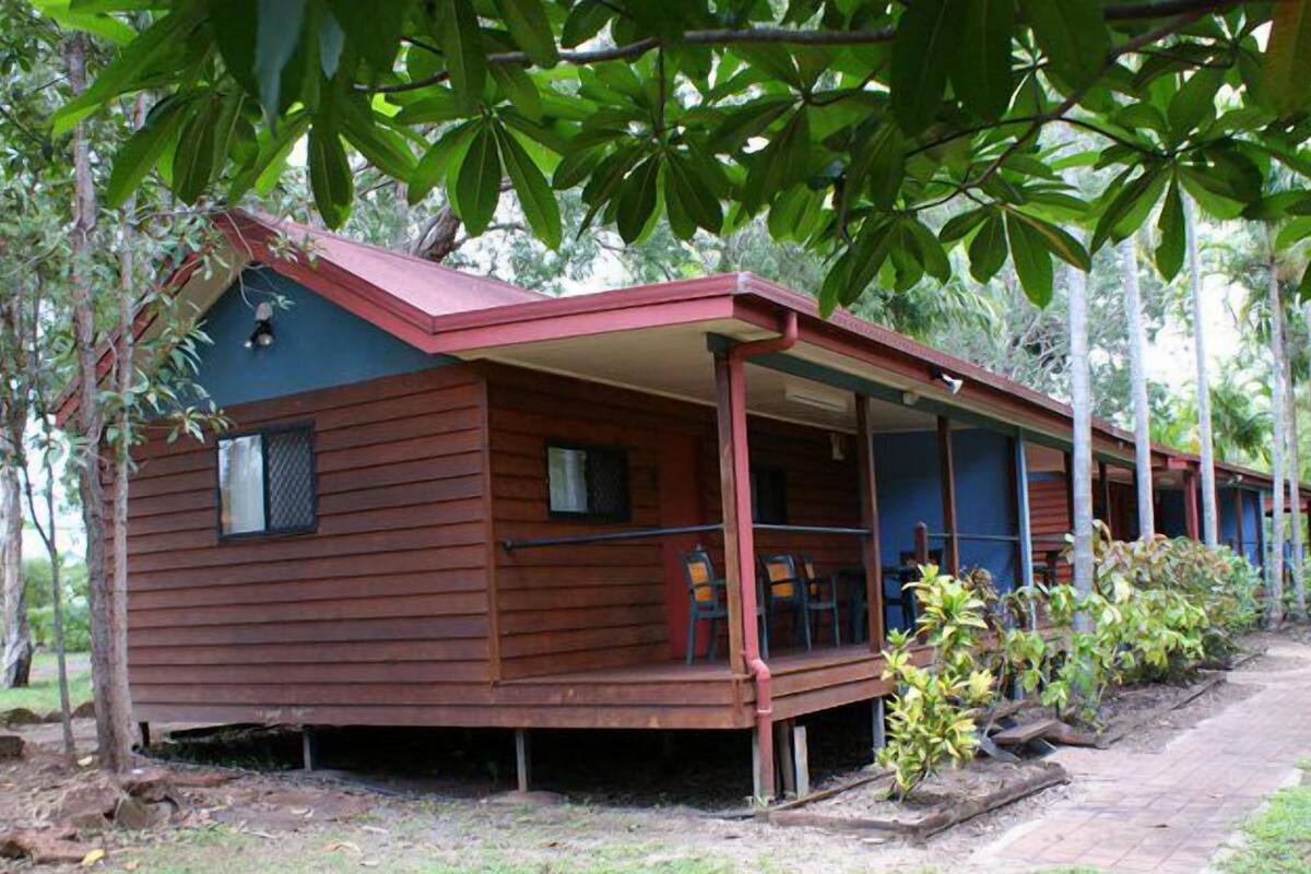 A wooden cabin with a porch, surrounded by trees.