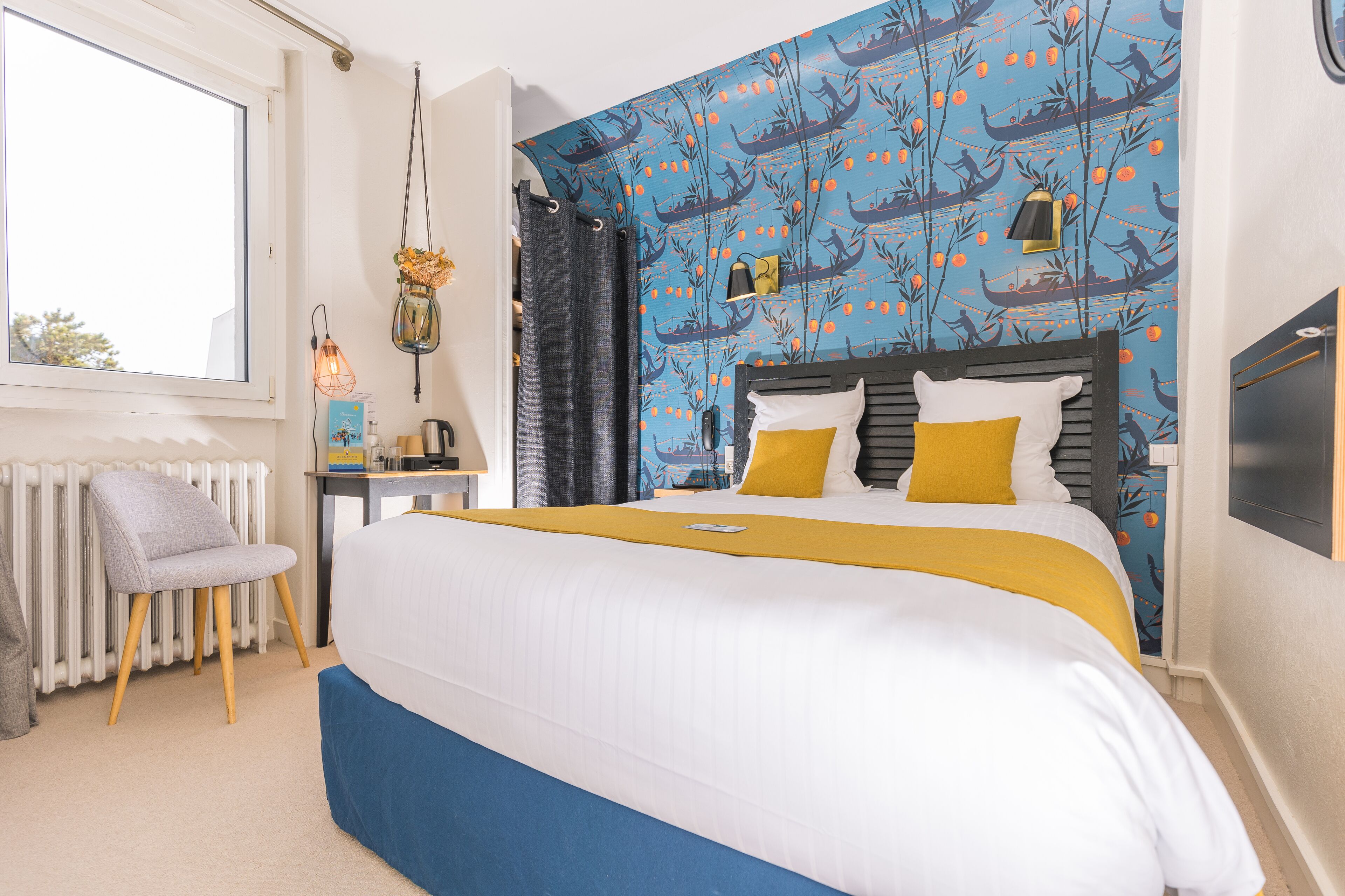 Ein Schlafzimmer mit einem Bett, einem Sessel, einer Heizung, einem Tisch und einer Wand mit blauem Muster.