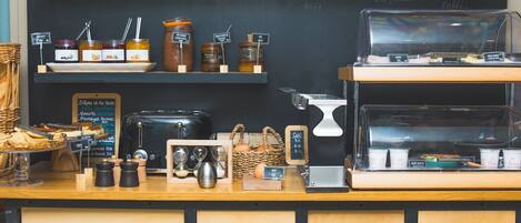 A coffee shop counter with jars of condiments, a coffee machine, and a chalkboard menu.