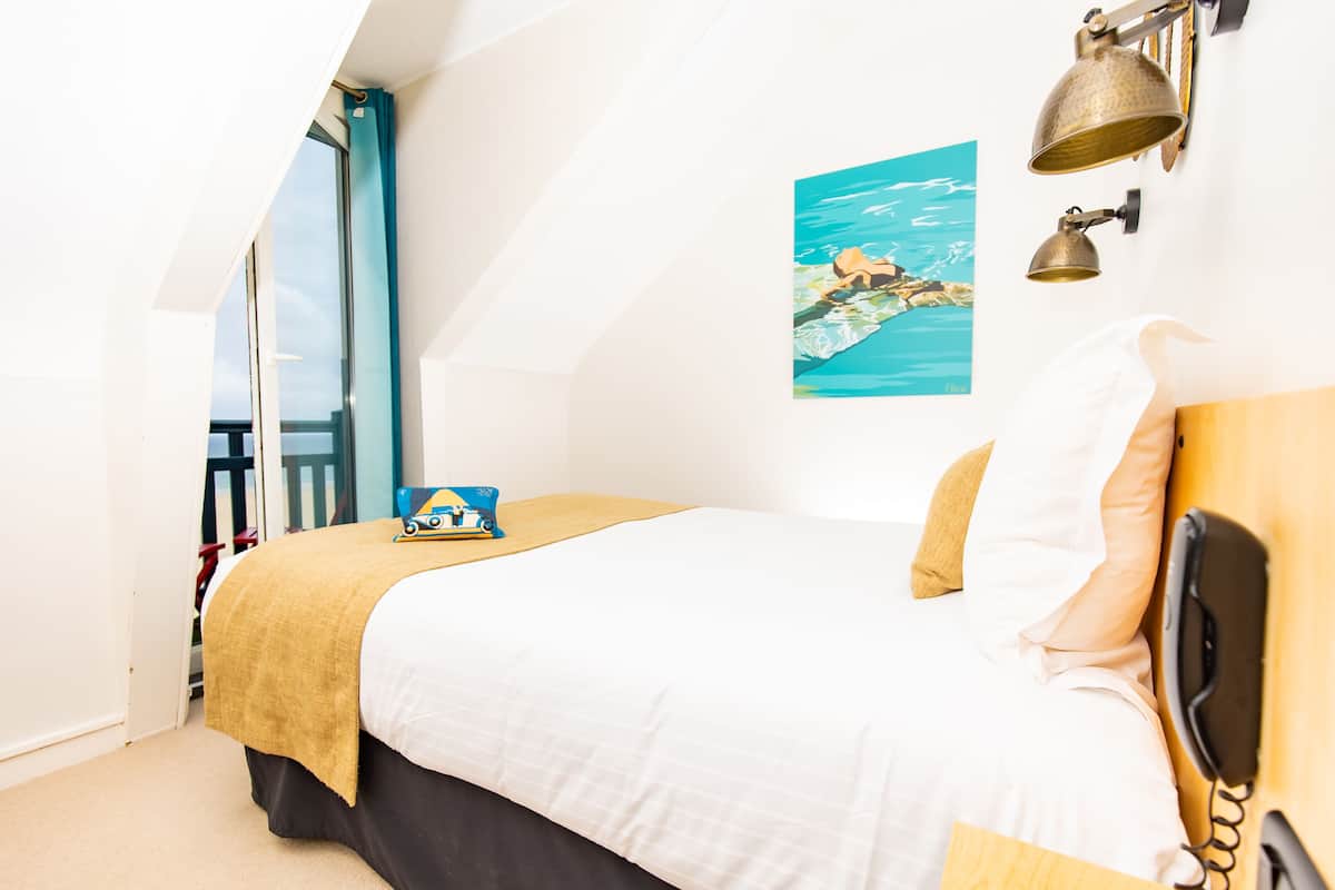 Een slaapkamer met een bed, een telefoon, een schilderij en een raam met uitzicht.