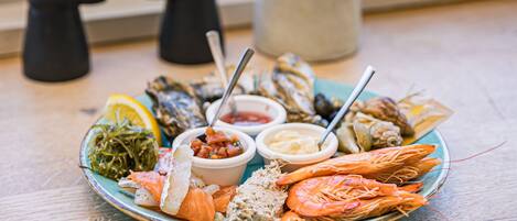 Un plato de mariscos sobre una mesa, con unos binoculares y un florero al fondo.