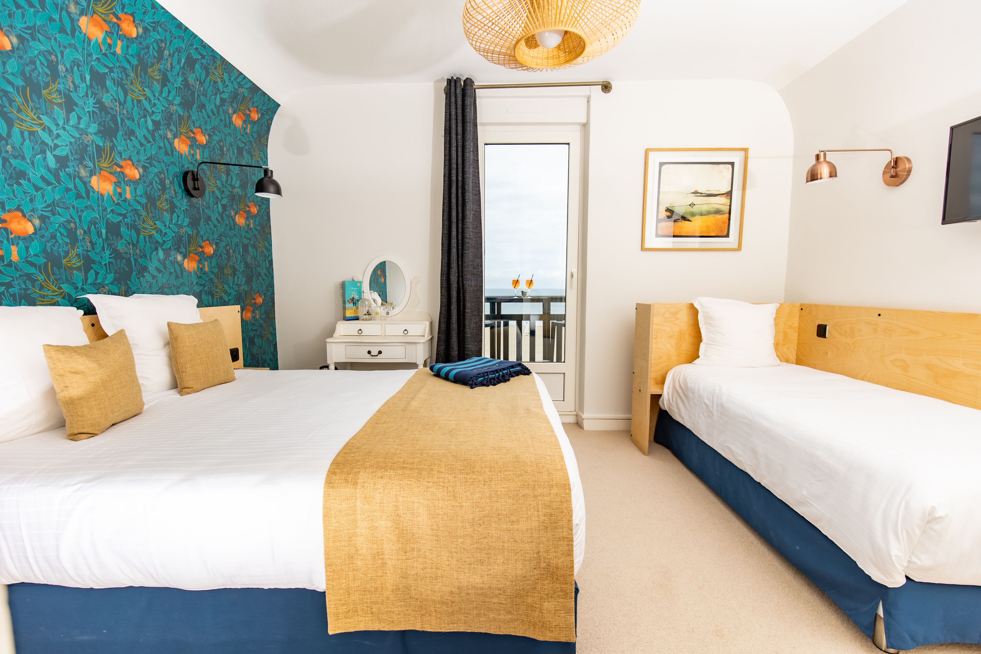 A hotel room with two beds, a large window, a view of the sea, a flat-screen TV, and a painting on the wall.