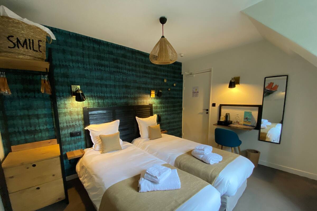 Een hotelkamer met een bed, nachtkastjes, een bureau, een stoel, een spiegel en een ophangsignet.