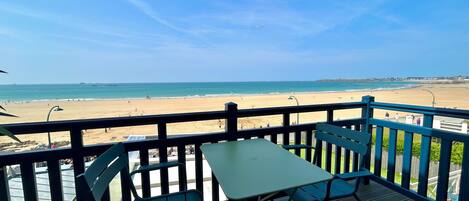 A deck with a table and chairs overlooking a beach.