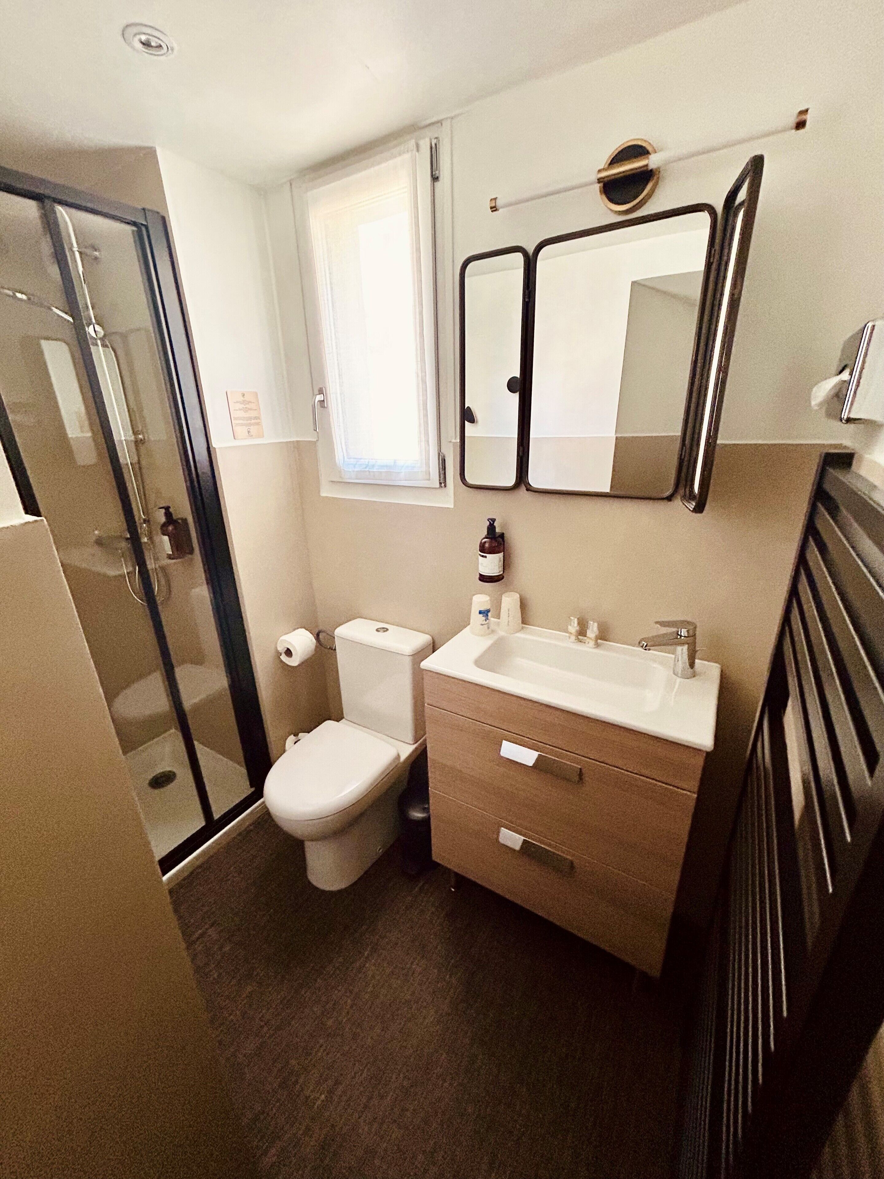 Une petite salle de bain comprenant des toilettes, un lavabo et une douche à parois de verre.