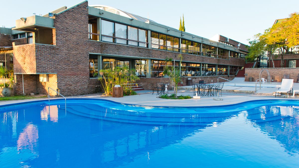 A modern building with a swimming pool, outdoor seating, and a brick facade.