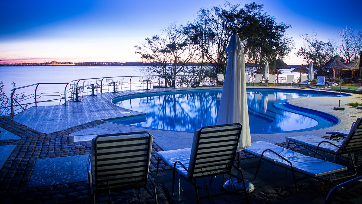 A pool with lounge chairs and a view of the water.